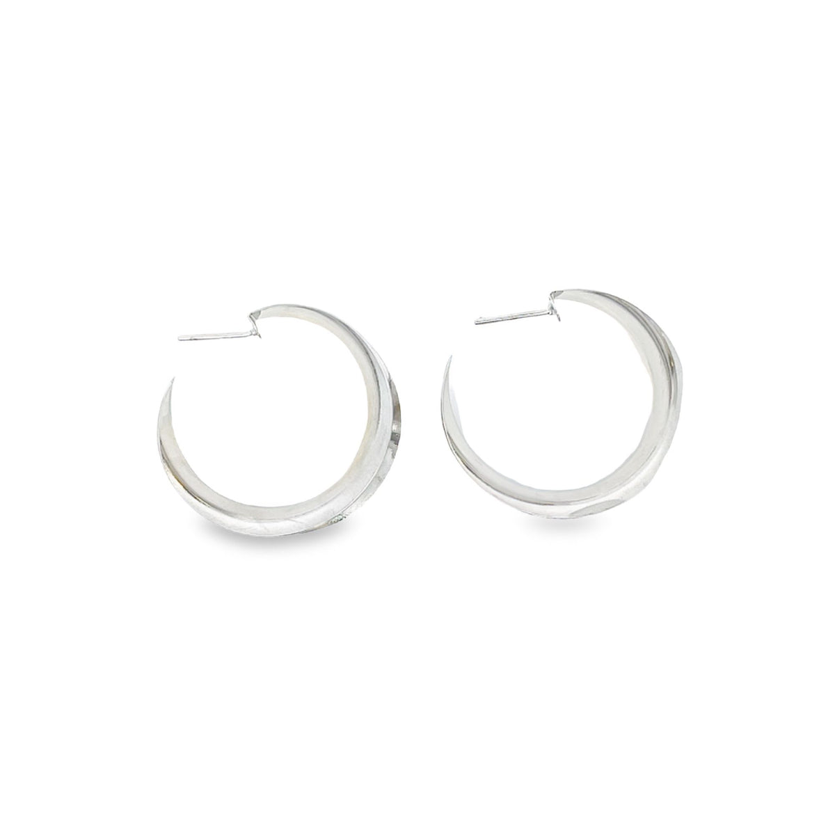 A pair of polished silver chunky crescent hoop earrings rests against a clean white background.