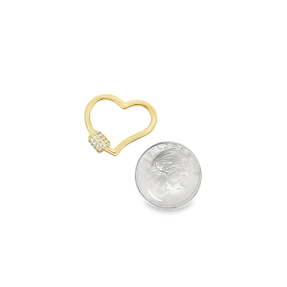 A gold heart-shaped charm with pavé diamonds rests next to a US quarter for scale.
