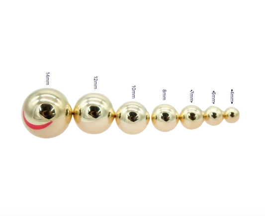 A row of polished gold metal balls displays a scale of sizes ranging from 14mm down to 4mm.