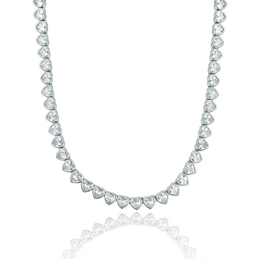 A silver heart-shaped tennis necklace sparkles against a clean white background, reflecting its glittering gemstones below.