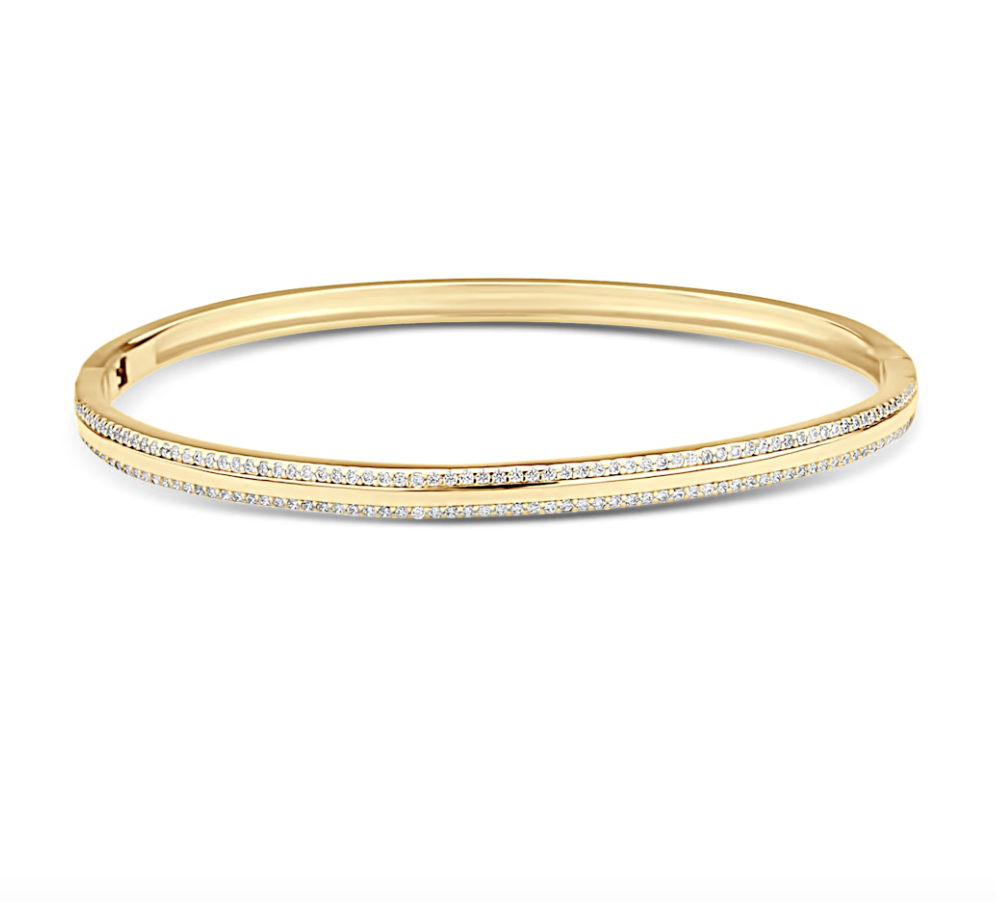 A polished gold bangle bracelet features two delicate rows of sparkling diamonds along its front curve.