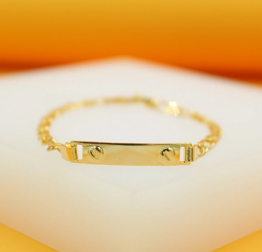 A shiny gold ID bracelet rests on a white display surface against a vibrant orange and white background.