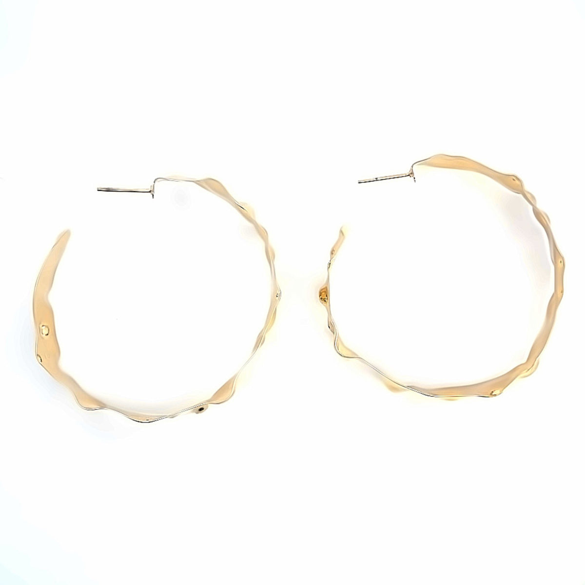 A pair of large, textured gold hoop earrings rests against a clean white background.