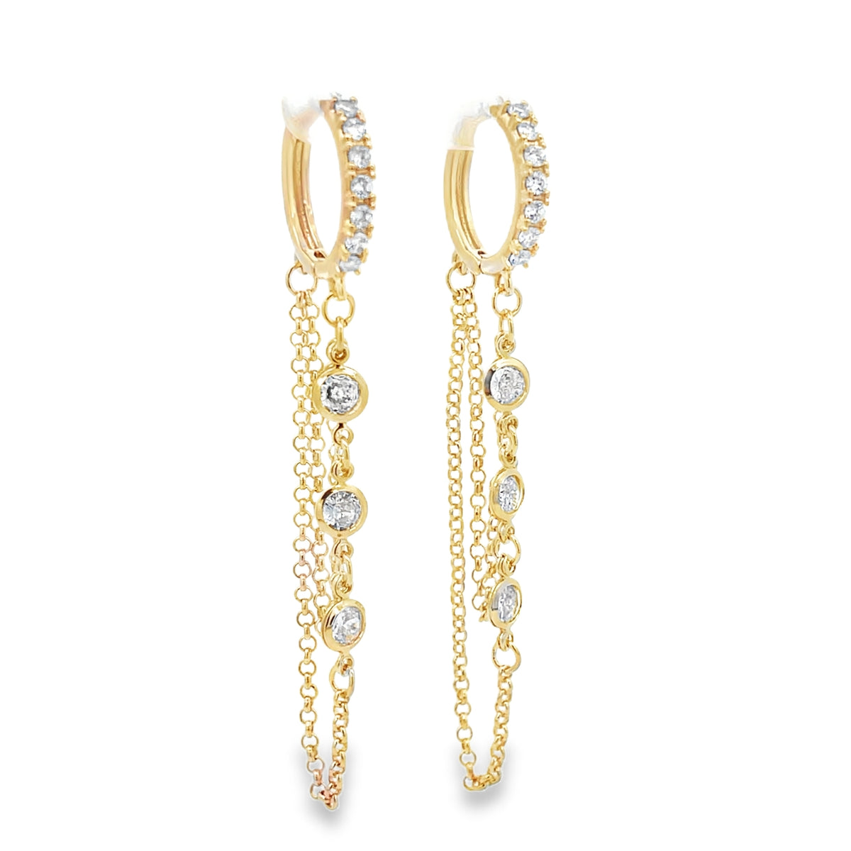 A pair of sparkling gold huggie hoop earrings featuring pavé diamonds and delicate dangling chains with bezel-set stones.