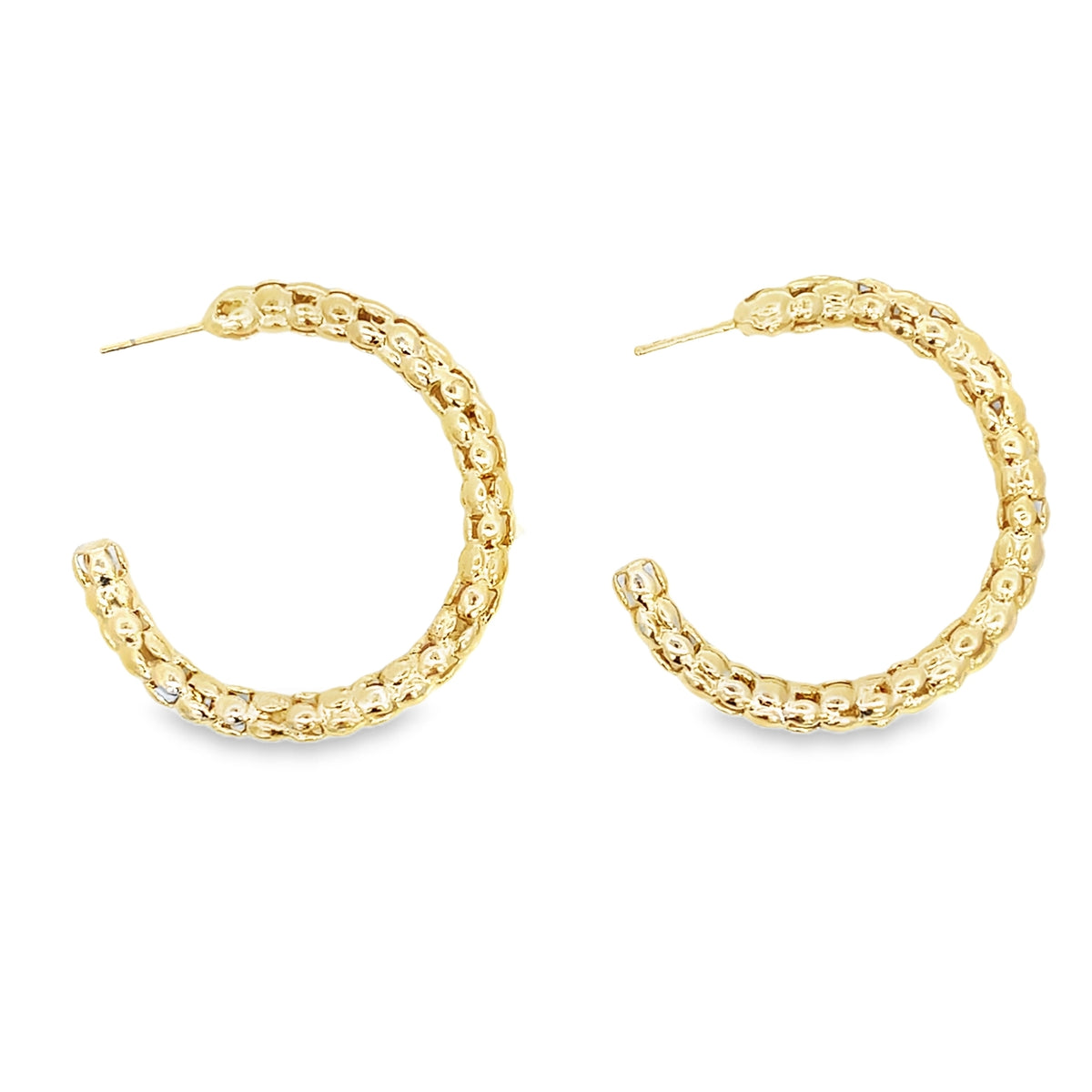 A pair of textured gold hoop earrings displays a beaded design against a white background.