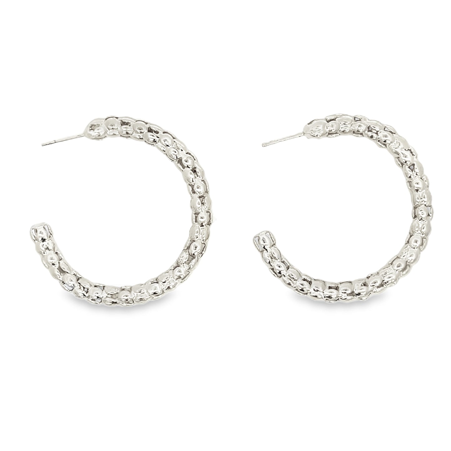 A pair of textured silver hoop earrings glimmers against a clean white background.