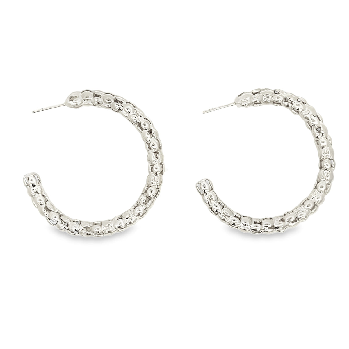 A pair of textured silver hoop earrings glimmers against a clean white background.