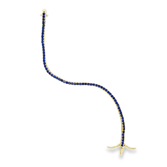 A graceful gold tennis bracelet sparkles with a continuous line of vibrant blue sapphires against a clean white background.