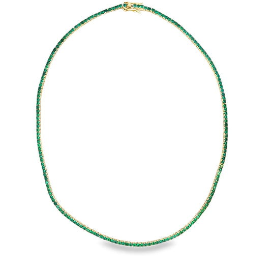 A delicate gold tennis necklace sparkles with vibrant green gemstones arranged in a continuous circle against a clean white background.