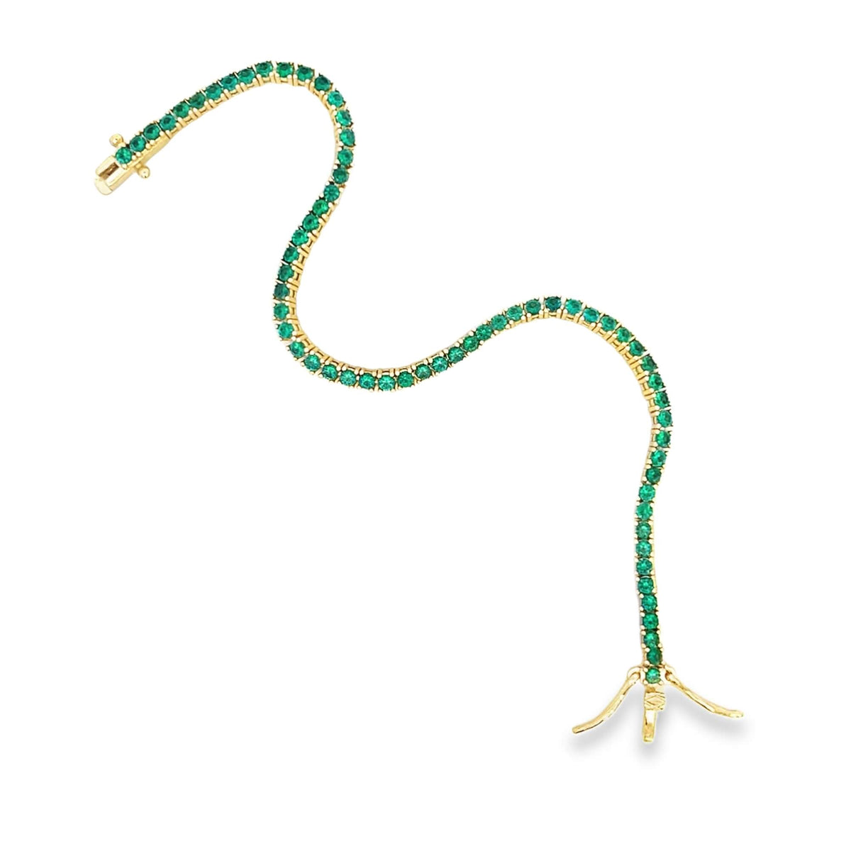 A sinuous gold tennis bracelet sparkles with vibrant green emerald stones against a clean white background.