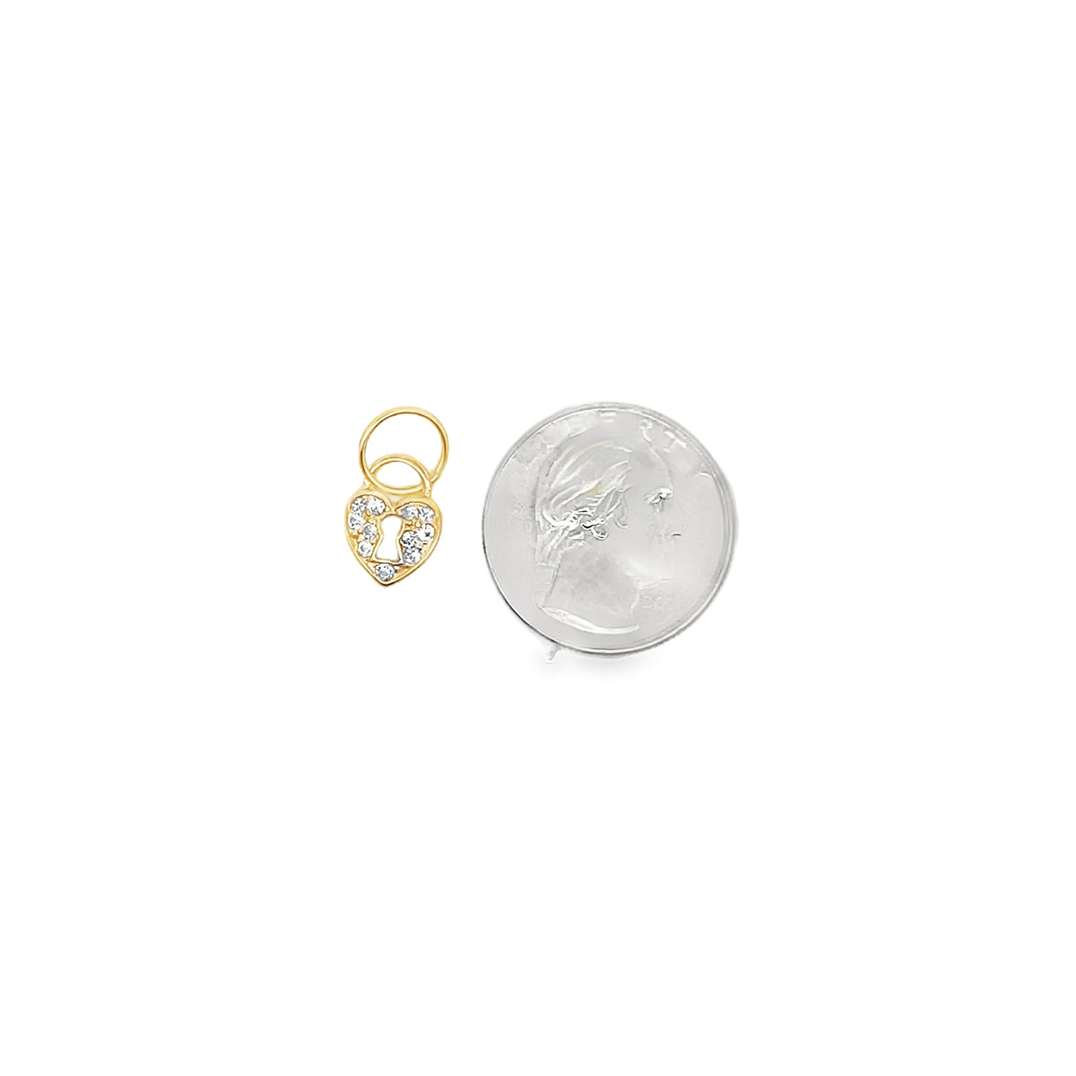 A dainty gold heart-shaped charm pendant encrusted with sparkling cubic zirconia sits beside a US quarter for scale.