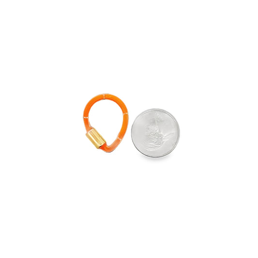 A small orange enamel and gold charm enhancer sits beside a US dime for size comparison.