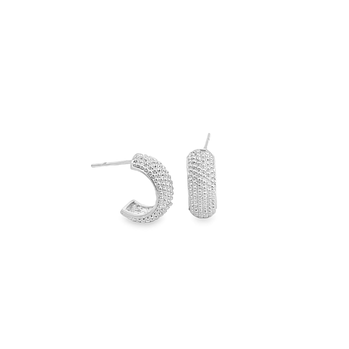 A pair of textured silver huggie hoop earrings with a beaded design sit against a clean white background.