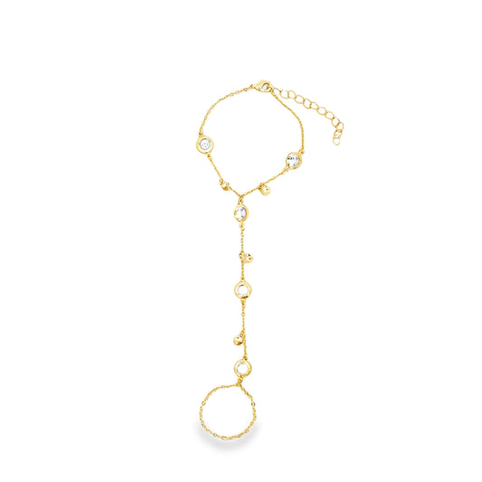 A delicate gold slave bracelet features sparkling bezel-set crystals and connects a wrist chain to a finger ring against a clean white background.