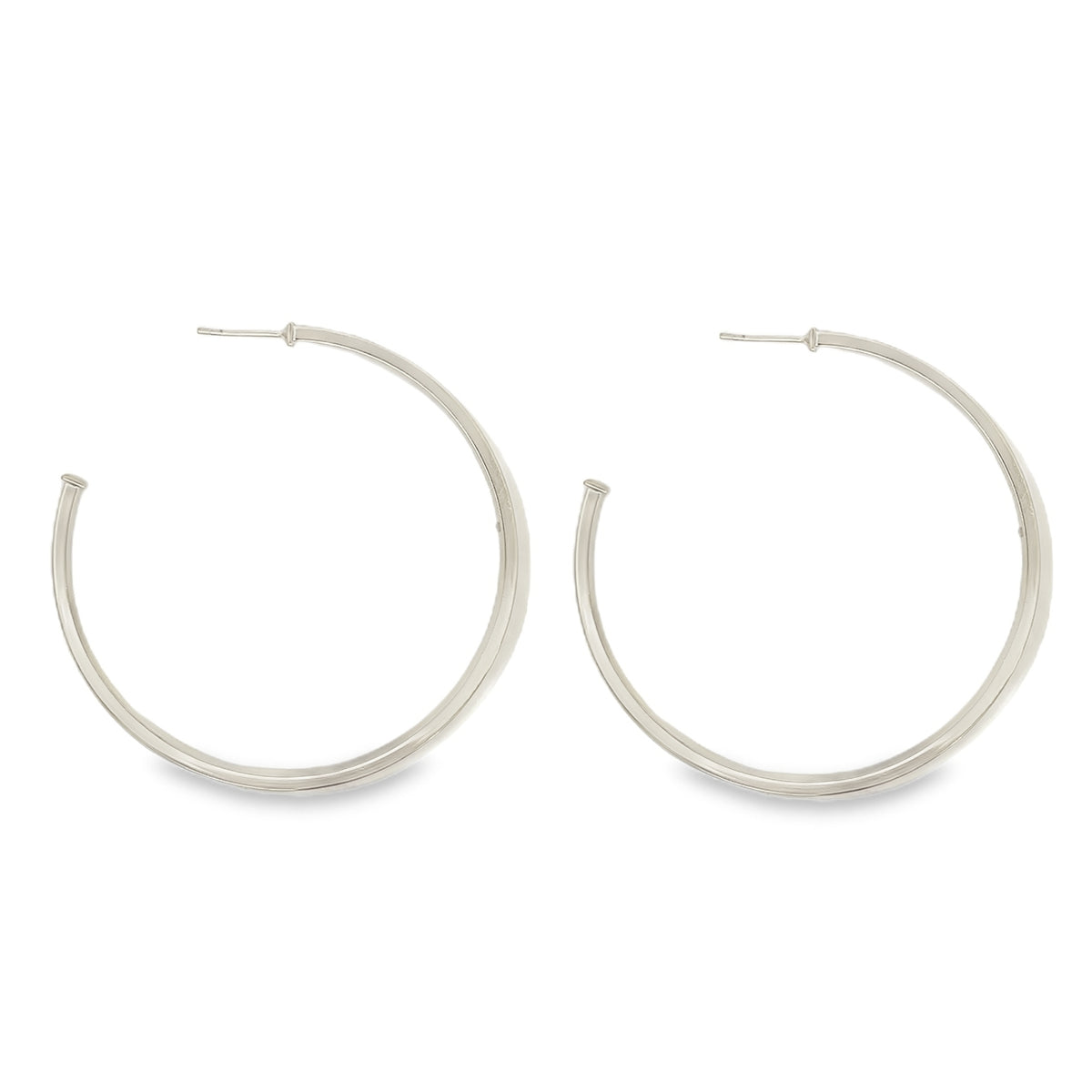 A pair of sleek, silver hoop earrings rests against a clean white background.