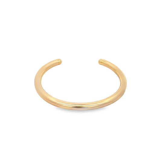 A minimalist gold cuff bracelet rests against a clean white background.