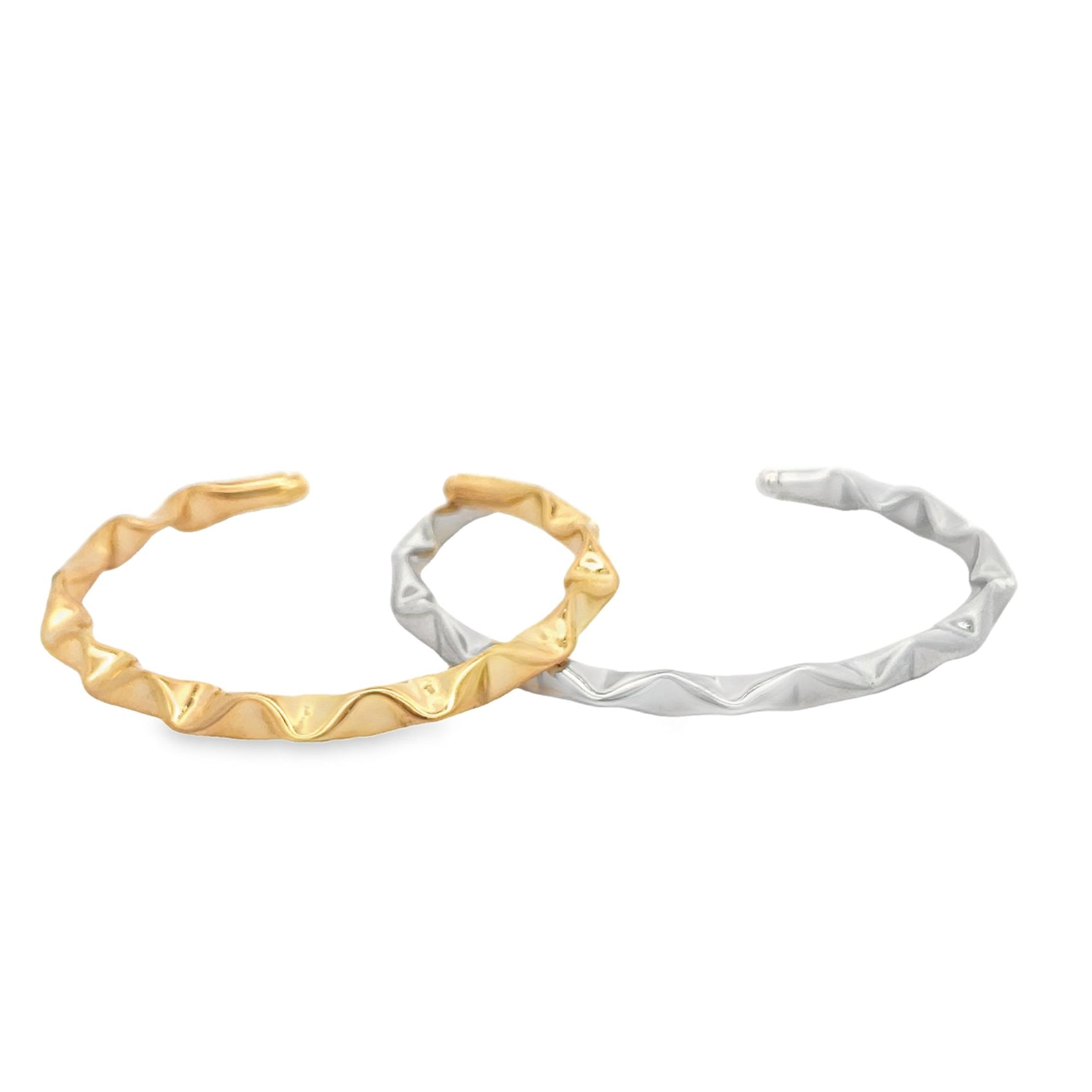 Two distinct wave-textured metal cuff bracelets, one in gold and one in silver, rest side by side against a clean white background.