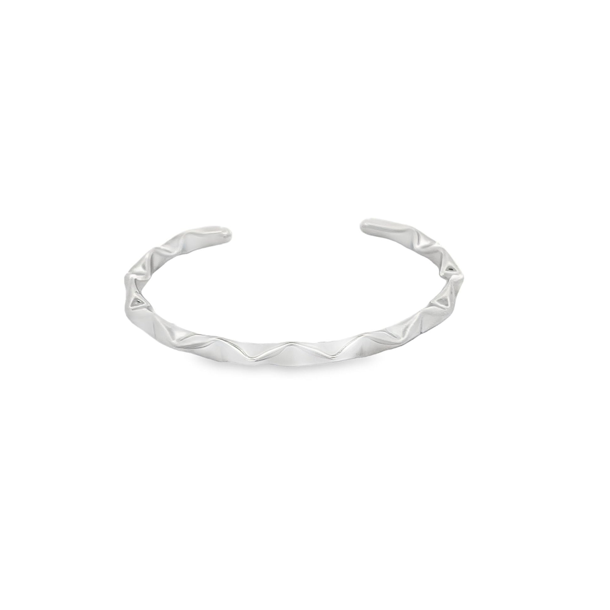 A sleek silver cuff bracelet rests against a plain white background, showcasing its unique wavy design.