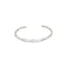 A sleek silver cuff bracelet rests against a plain white background, showcasing its unique wavy design.