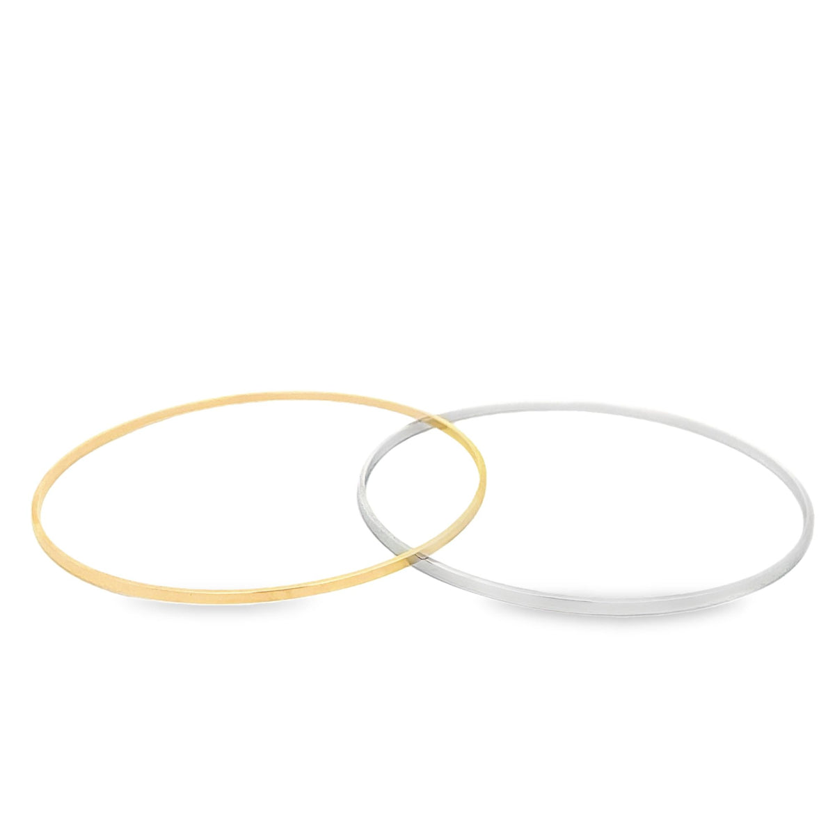A yellow gold bangle and a white gold bangle rest side by side on a white surface, showcasing their sleek, minimalist design.