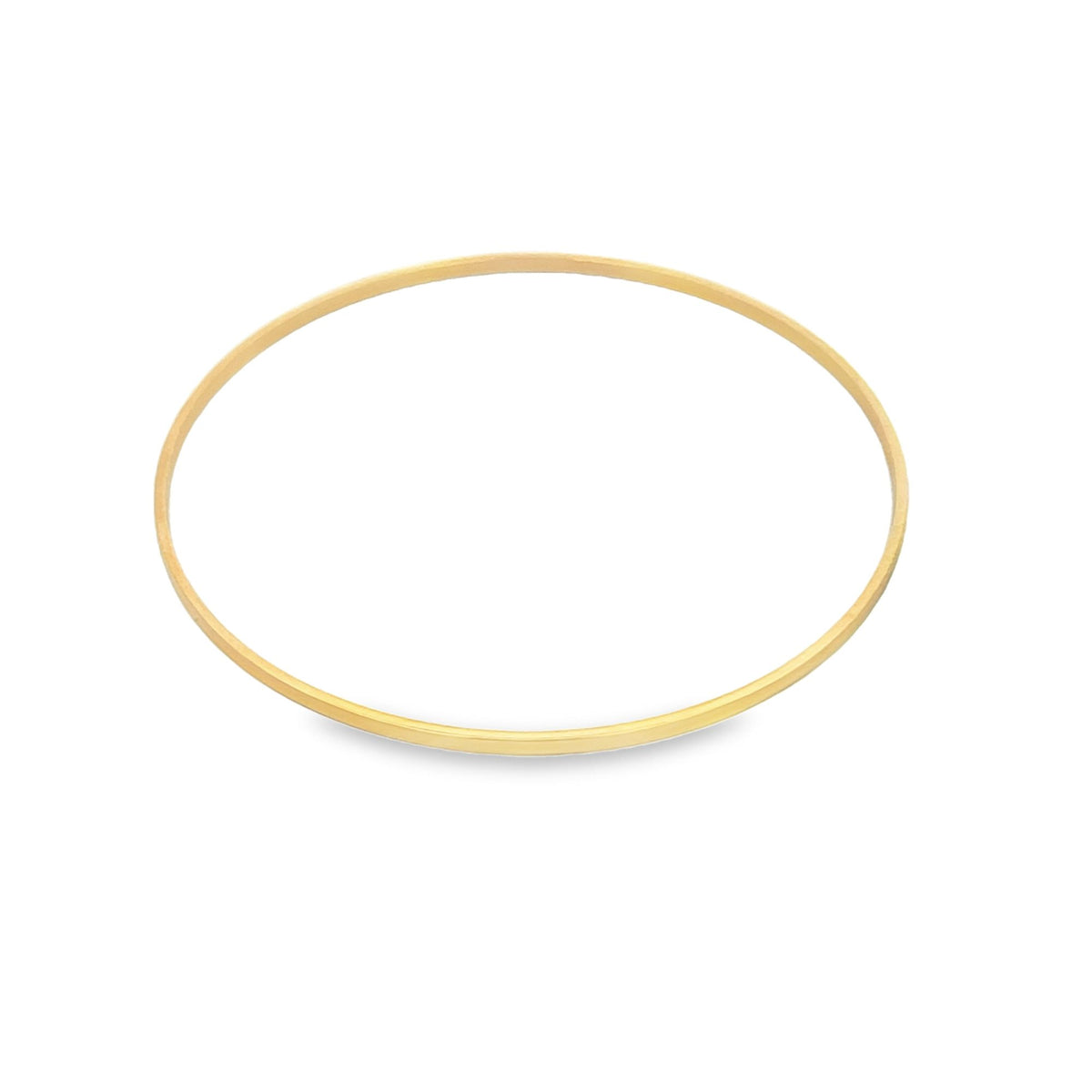A simple thin gold bangle bracelet rests against a clean white background.