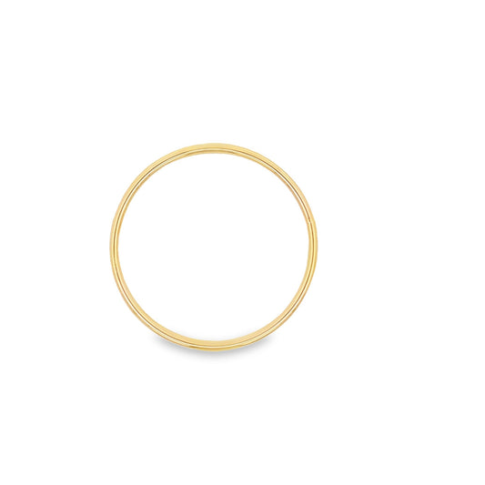A sleek minimalist yellow gold stacking ring rests on a clean white surface.
