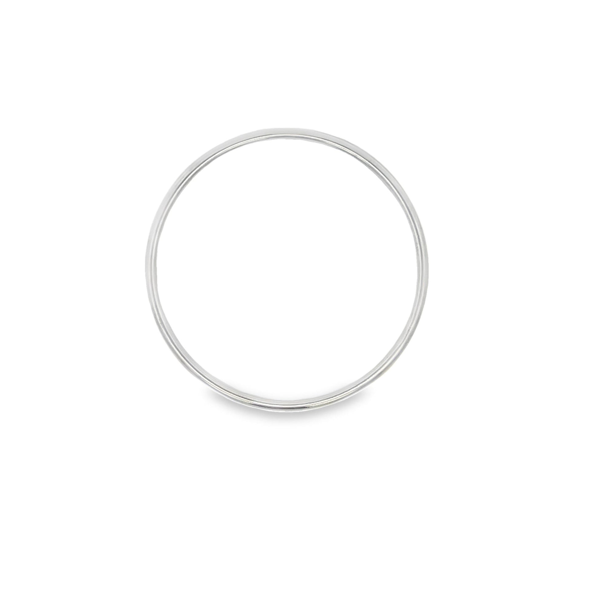 A minimalist silver band ring rests flat against a clean white background, casting a soft shadow beneath it.