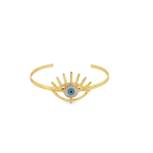 A gold cuff bracelet features an evil eye charm with blue, white, and black enamel.