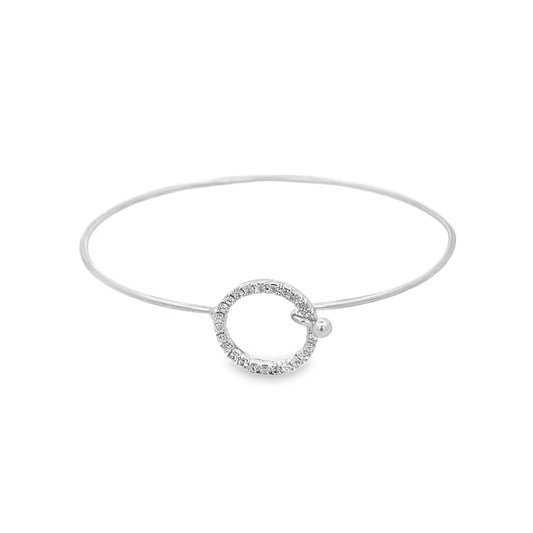 A delicate silver bangle bracelet features a sparkling pavé-set diamond circle charm as its centerpiece against a clean white background.