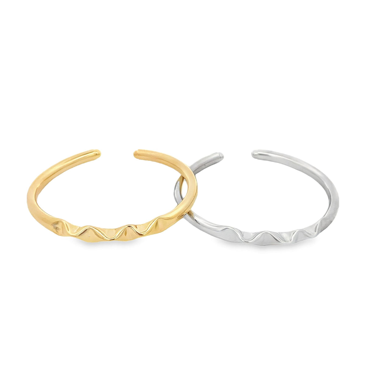 Two open wave rings in gold and silver rest side by side on a plain white background.