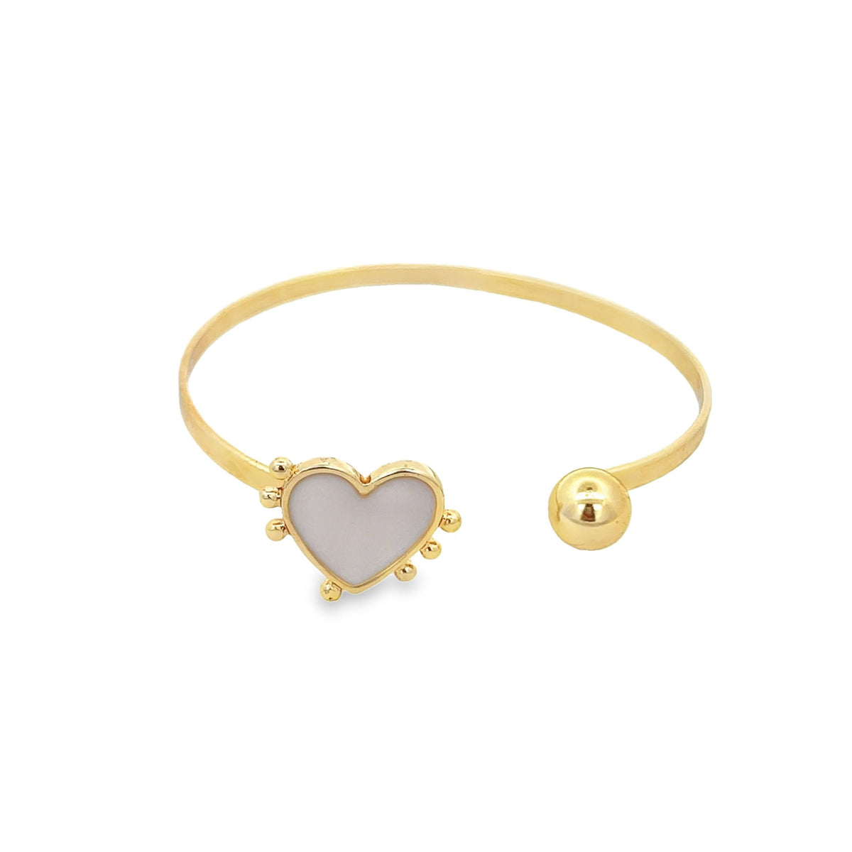 A gold cuff bracelet features a mother-of-pearl heart charm on one end and a polished gold sphere on the other.