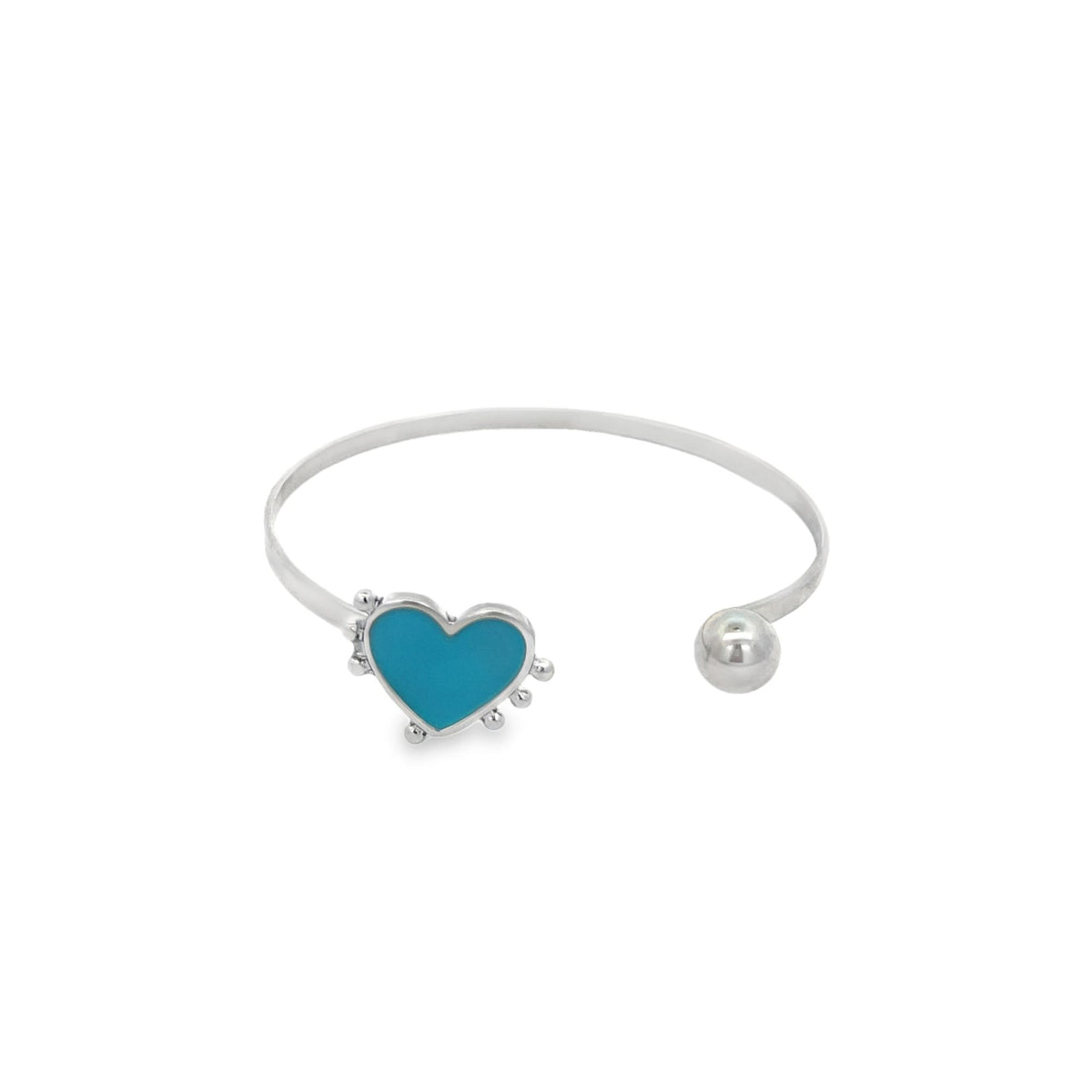 A silver cuff bracelet features a vibrant blue enamel heart on one end and a polished ball on the other.