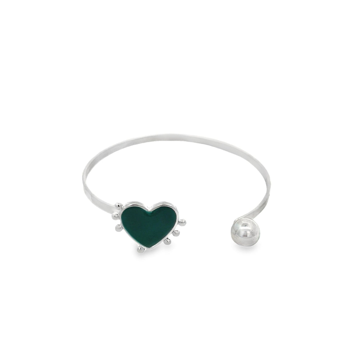 A silver cuff bracelet features a green enamel heart charm on one end and a polished ball on the other against a white background.