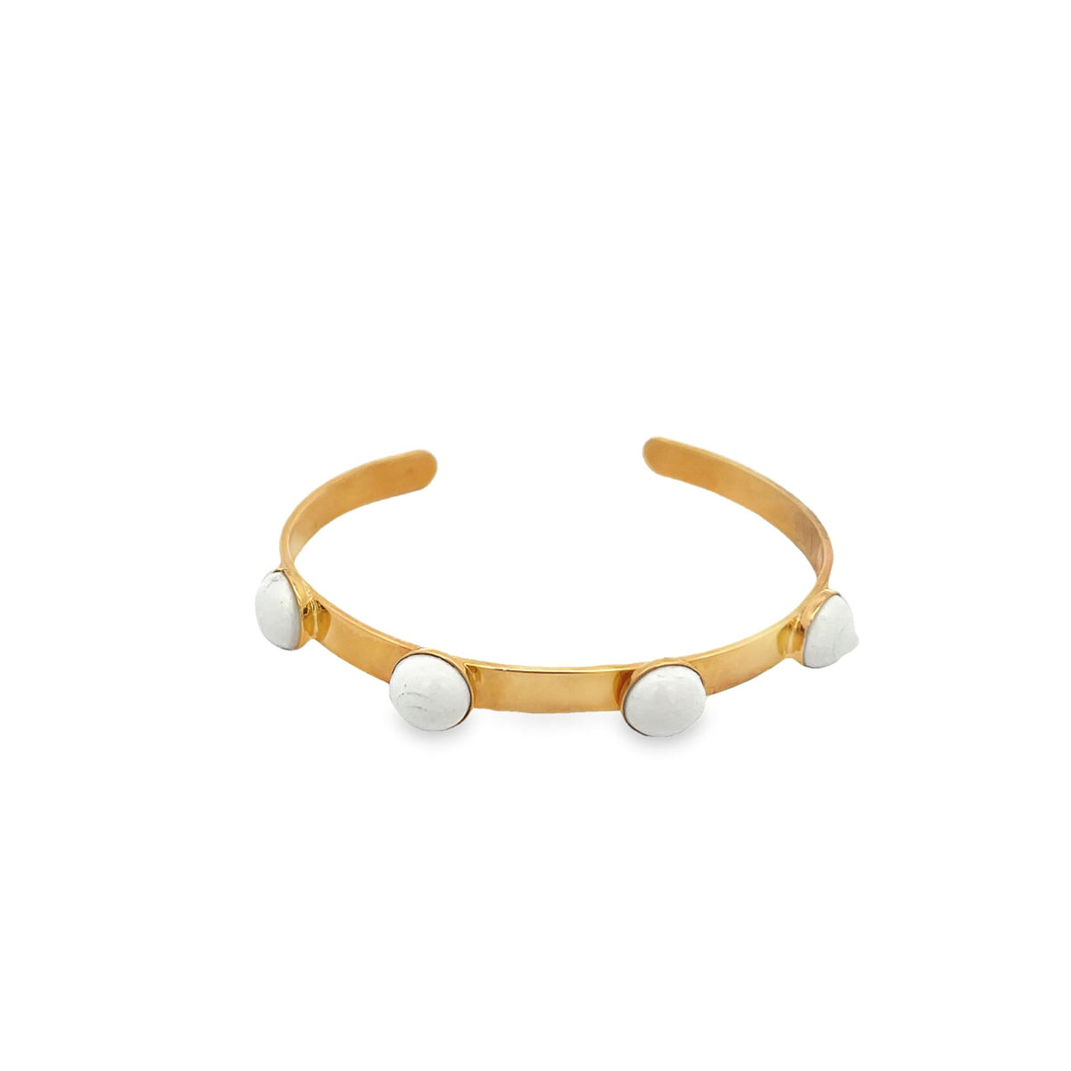 A sleek gold cuff bracelet features four round white howlite stones set evenly across its band.