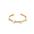 A sleek gold cuff bracelet features four round white howlite stones set evenly across its band.