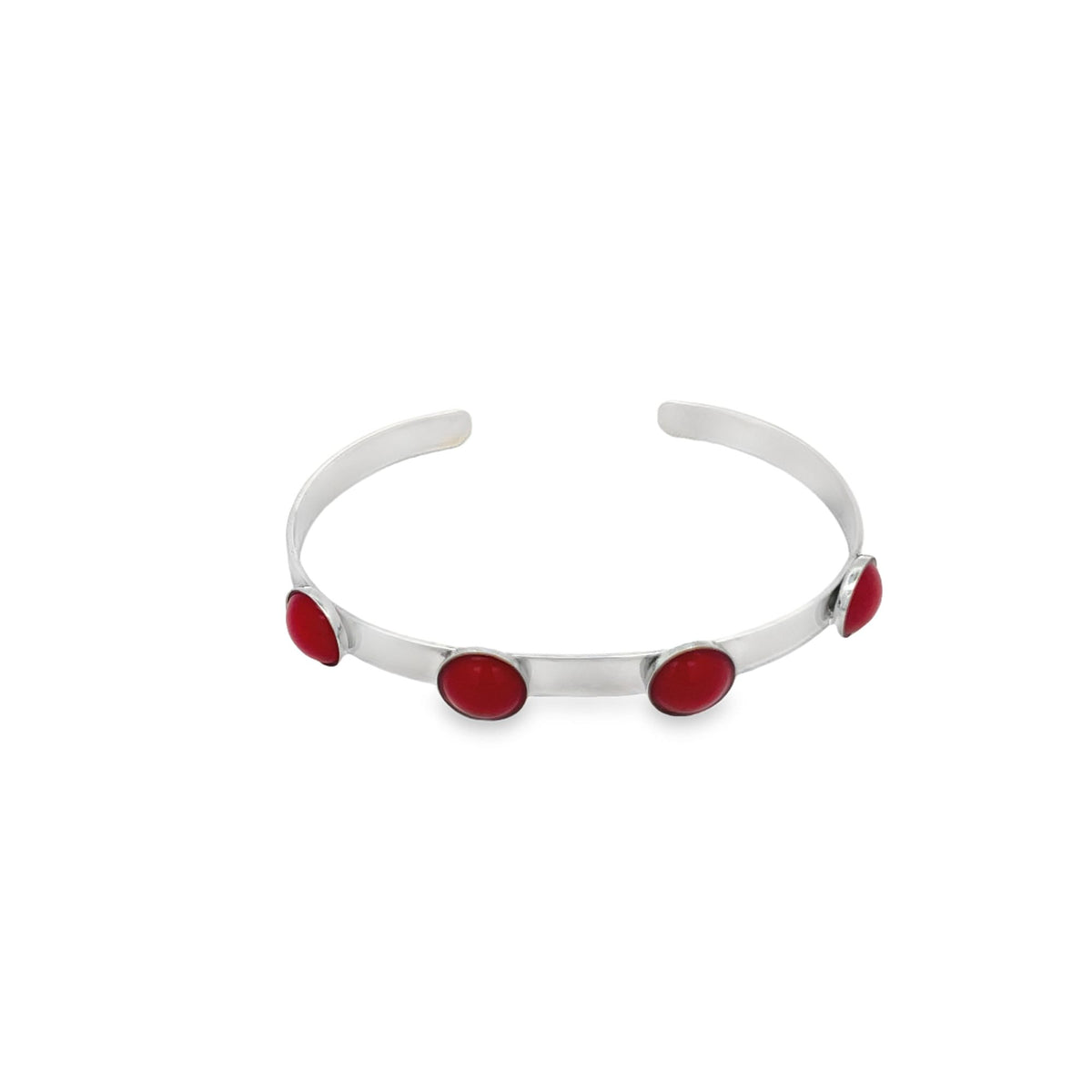 A sleek silver cuff bracelet features four vibrant red cabochon stones embedded along its band against a plain white background.