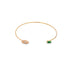 A delicate gold cuff bracelet features an evil eye motif set with a sparkling diamond on one end and a vibrant emerald gemstone on the other.