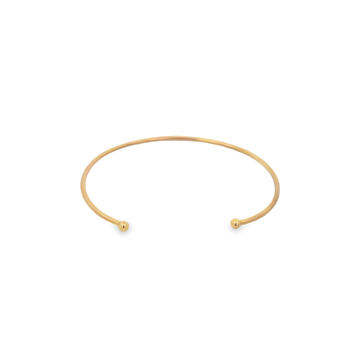 A minimalist gold cuff bracelet rests on a white background, featuring polished ball ends on each open tip.