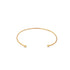 A minimalist gold cuff bracelet rests on a white background, featuring polished ball ends on each open tip.
