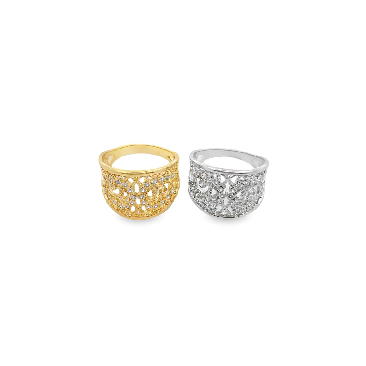 A gold ring and a silver ring with intricate filigree designs and sparkling cubic zirconia stones rest side by side on a white surface.