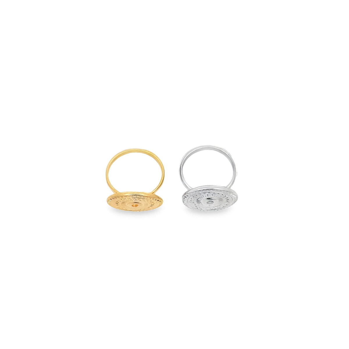 Two intricate, coin-shaped rings rest on a white surface, with one finished in polished gold and the other in sleek silver.