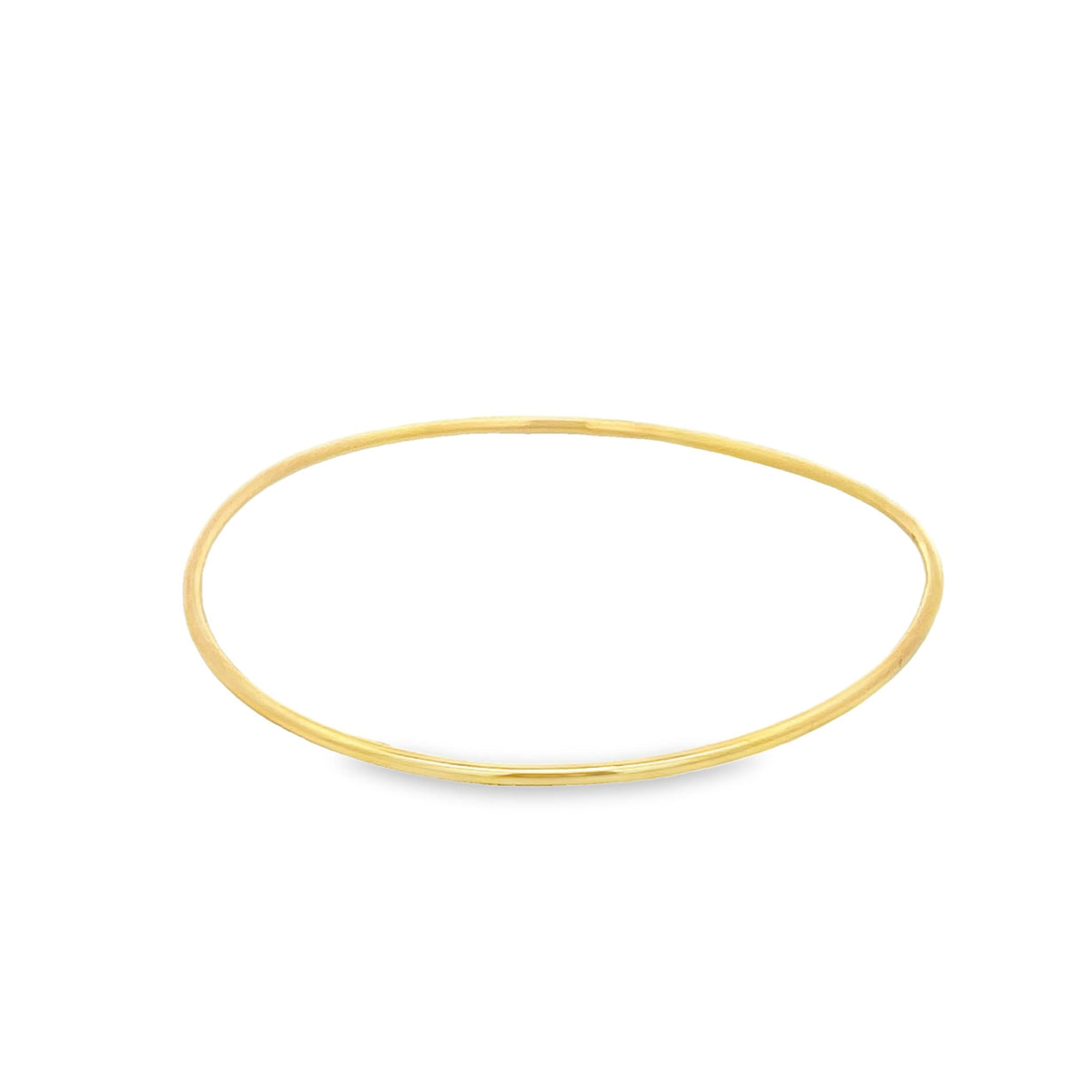 A sleek gold wire bangle rests against a clean white background.