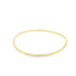 A sleek gold wire bangle rests against a clean white background.