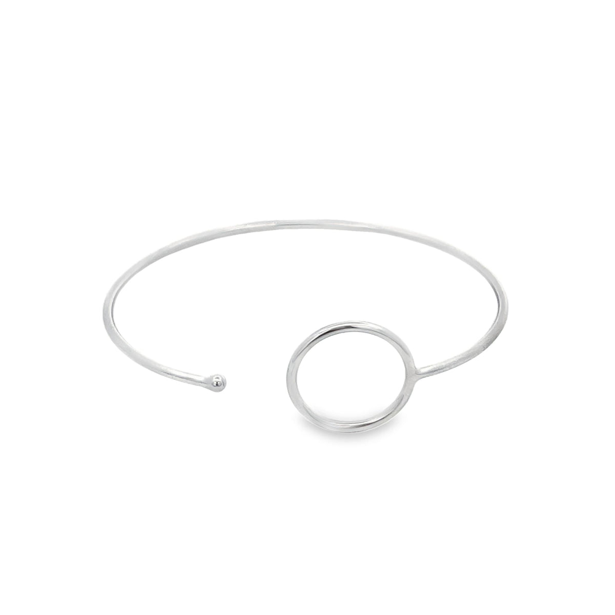 A minimalist silver cuff bracelet features an open-ended design accented with a delicate circle charm on a white background.