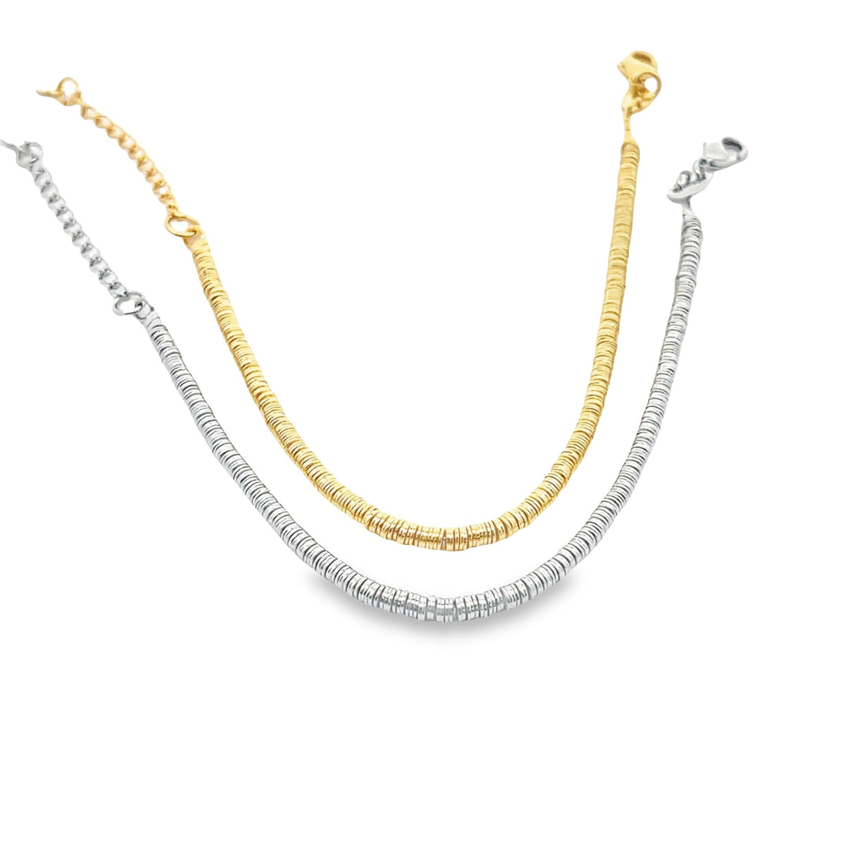 Two layered disk-bead necklaces, one in gold and one in silver, curve gracefully against a white background.