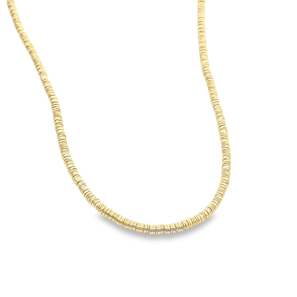 A minimalist gold beaded disk necklace rests against a plain white background.