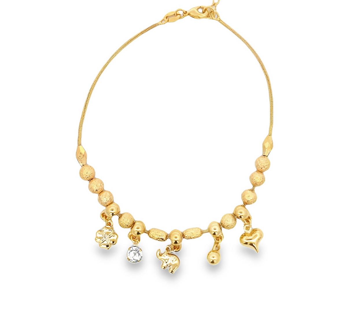 A delicate gold chain bracelet features assorted charms including a clover, a sparkling gemstone, an elephant, and a heart against a plain white background.