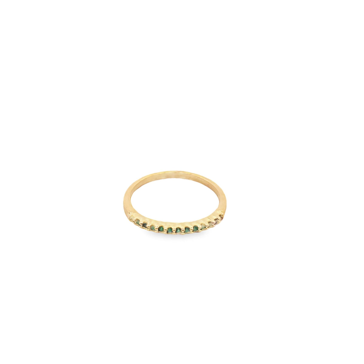 A delicate gold band ring showcases a row of sparkling green emerald gemstones prong-set across the front.