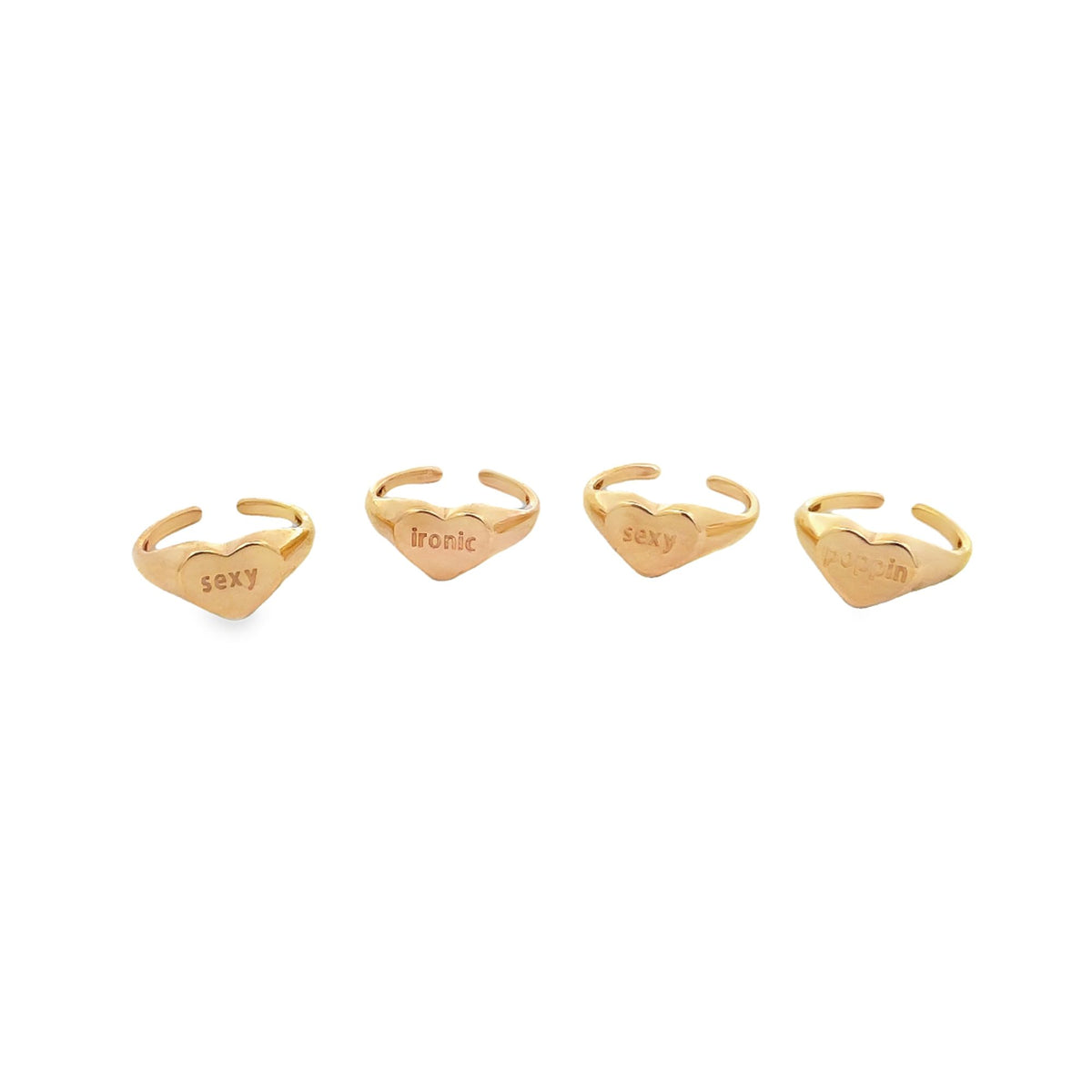 Four gold heart-shaped signet rings with engraved words are arranged in a row on a white background.