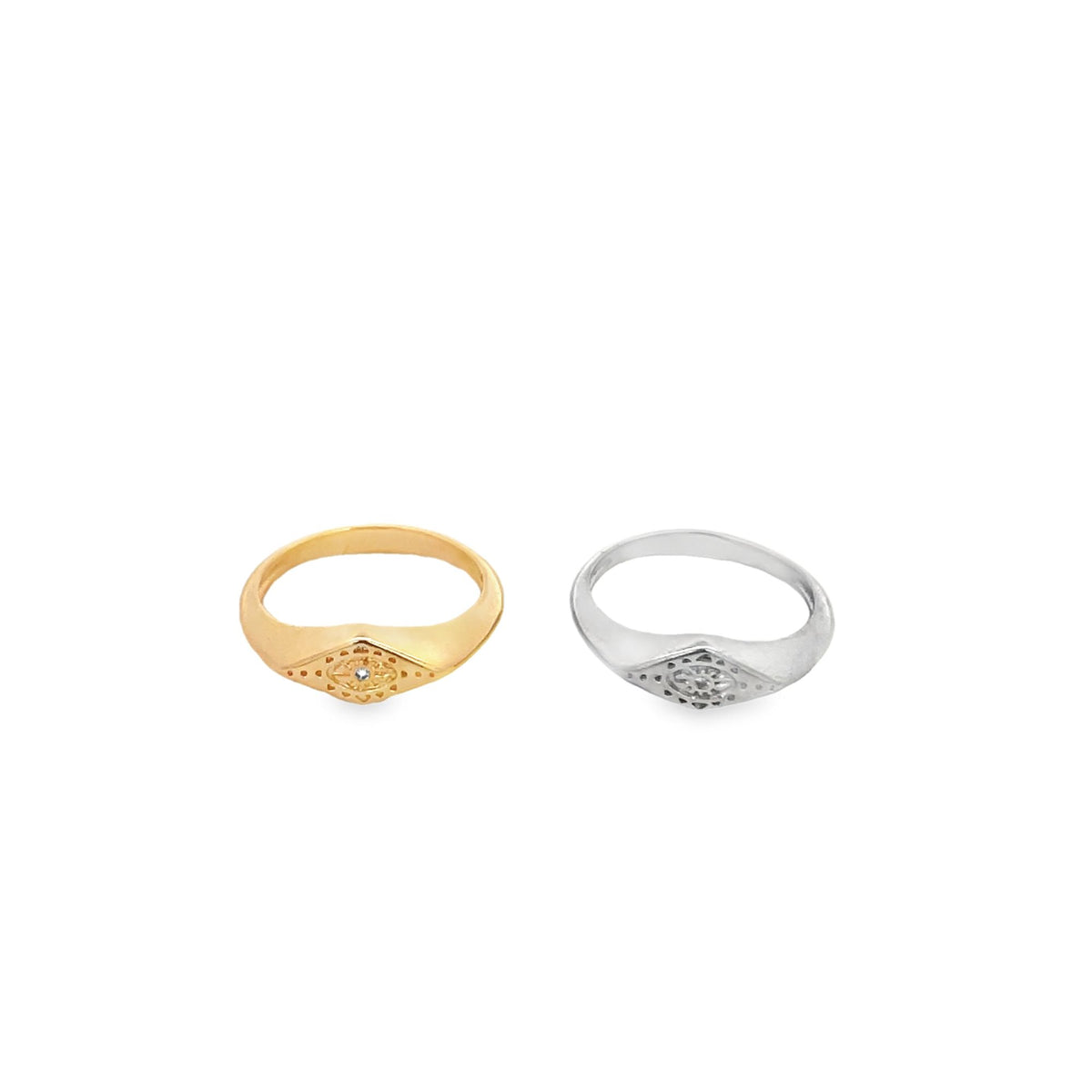 Two signet rings featuring evil eye designs, one in gold and the other in silver, rest side by side against a clean white background.